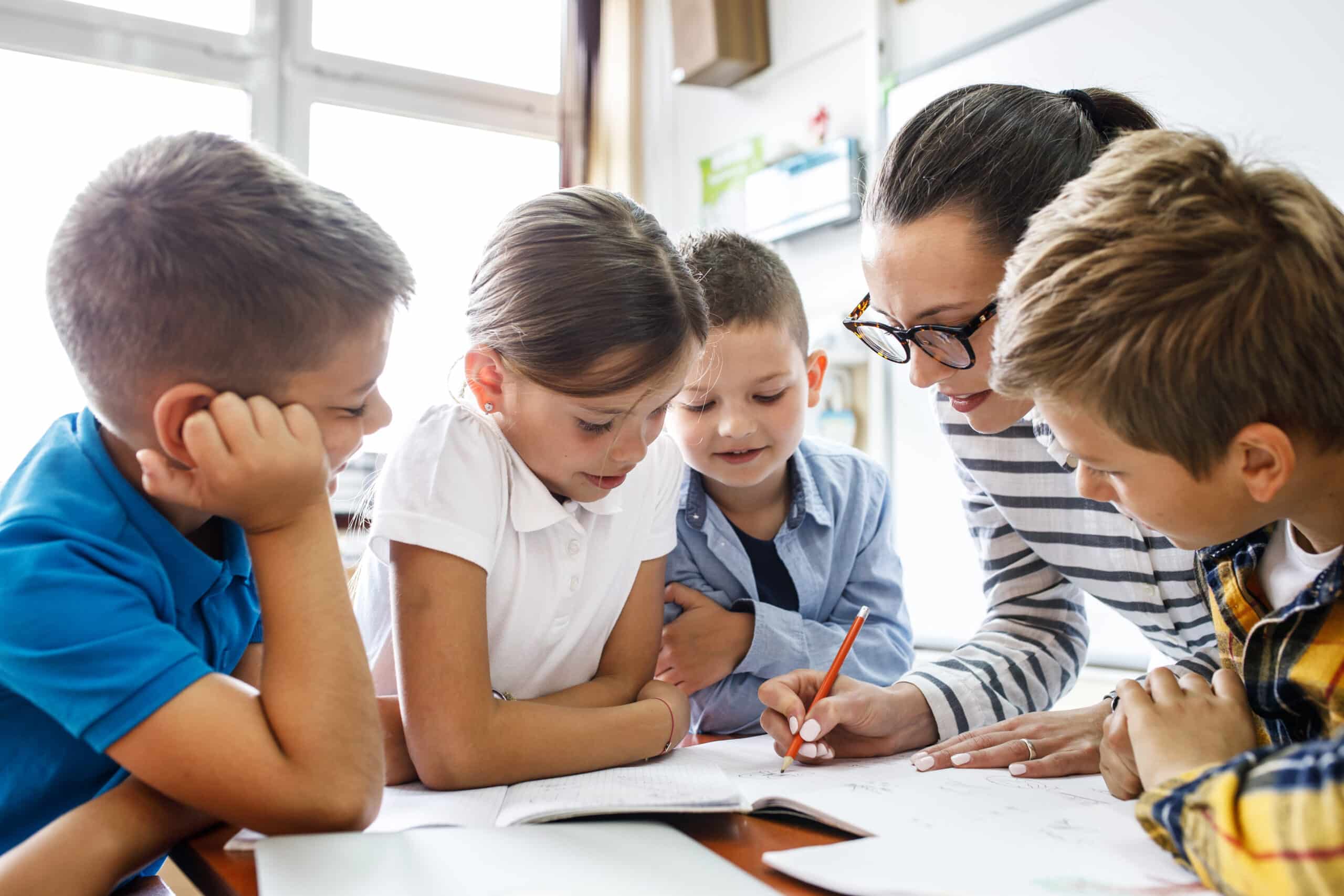 Student thoughtfully completing a challenging assignment, guided by a teacher — building resilience through learning.