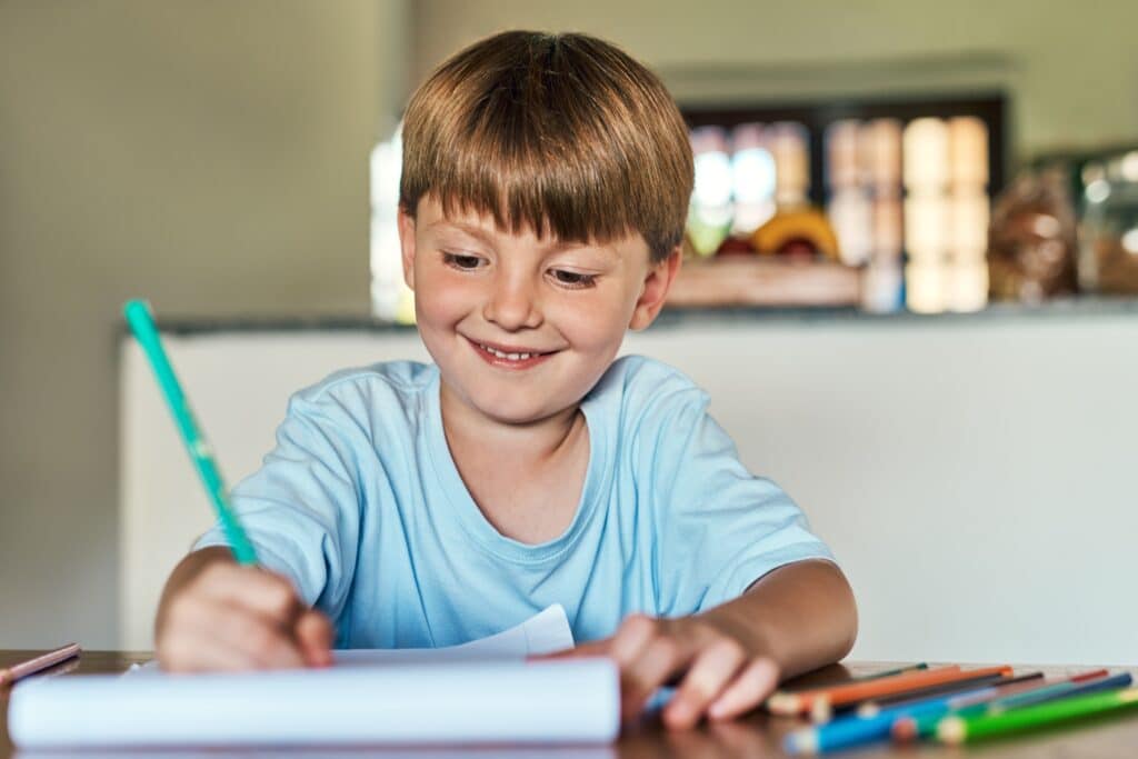 Child practicing handwriting with focused expression, showing perseverance and learning through effort.